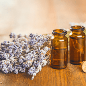 Amber glass bottles sit alongside a bouquet of dried lavender, evoking a sense of natural wellness and hinting at the use of essential oils in holistic health practices, perhaps as part of a hair care regimen emphasizing natural ingredients.