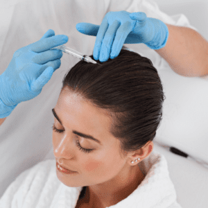 A patient undergoes a scalp treatment, where a practitioner in sterile blue gloves administers an injection, suggesting a clinical procedure for hair health, performed in a serene environment as the patient appears relaxed and at ease.